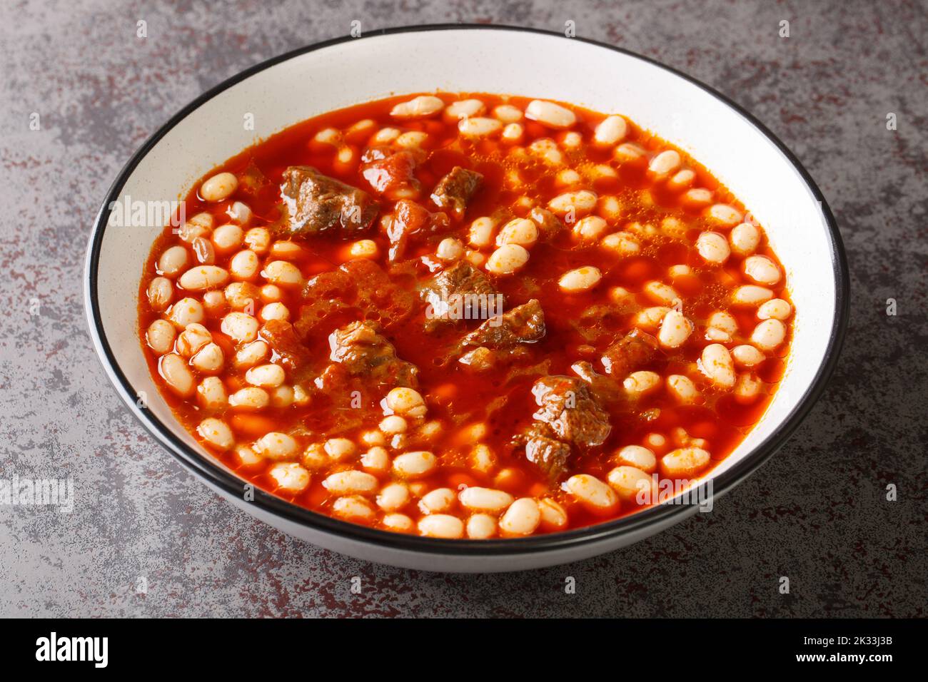 Türkischer Weißbohneneintopf mit Fleisch Etli kuru fasulye aus nächster Nähe auf dem Teller auf dem Tisch. Horizontal Stockfoto