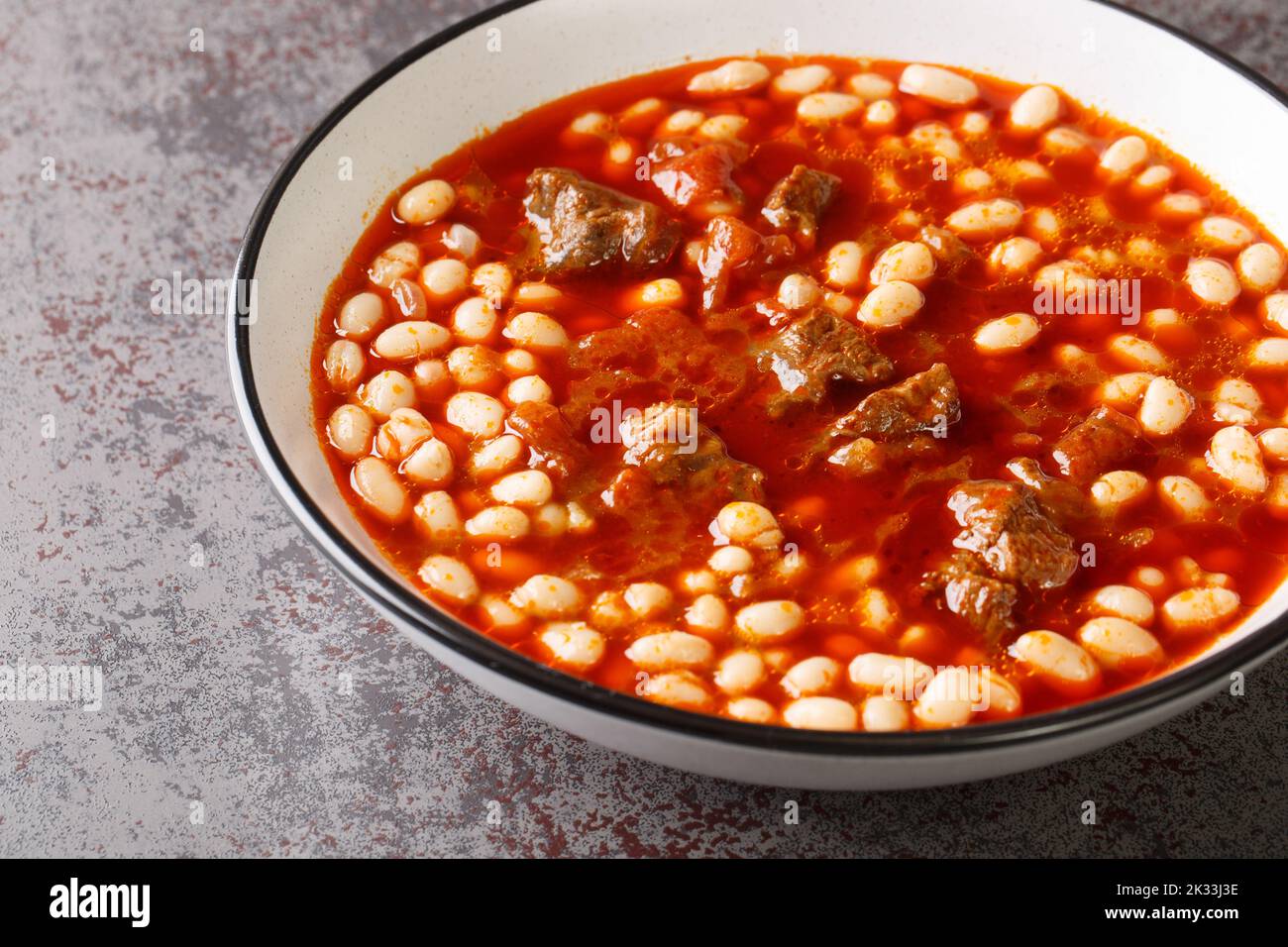 Würzige Kuru Fasulye aus Bohnen mit Lamm in Tomatensauce in einer Schüssel auf dem Tisch aus nächster Nähe einkochen. Horizontal Stockfoto