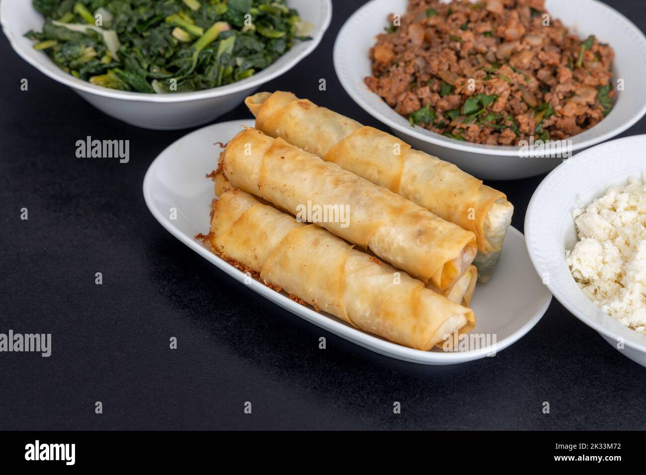 Türkische Rollen In Zigarrenform. Traditionelle Borek, Burek, gekochte, gegrillte frische Frühlingsrollen Essen auf schwarzem Hintergrund. Kopierbereich, Draufsicht. Stockfoto