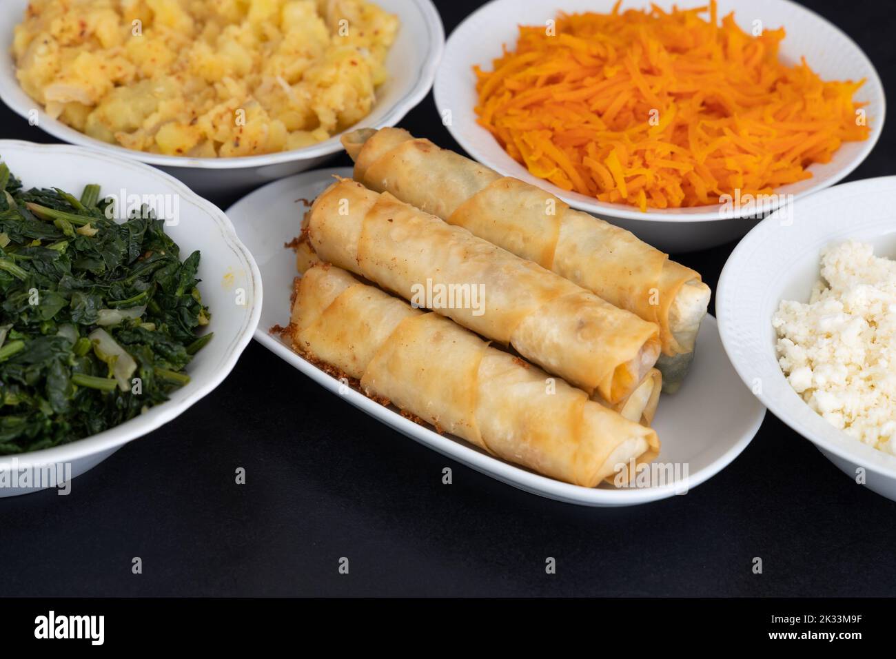 Türkische Rollen In Zigarrenform. Traditionelle Borek, Burek, gekochte, gegrillte frische Frühlingsrollen Essen auf schwarzem Hintergrund. Kopierbereich, Draufsicht. Stockfoto