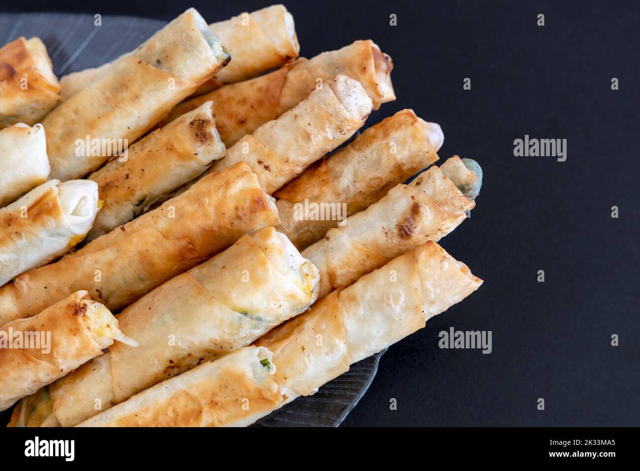 Türkische Rollen In Zigarrenform. Traditionelle Borek, Burek, gekochte, gegrillte frische Frühlingsrollen Essen auf schwarzem Hintergrund. Kopierbereich, Draufsicht. Stockfoto