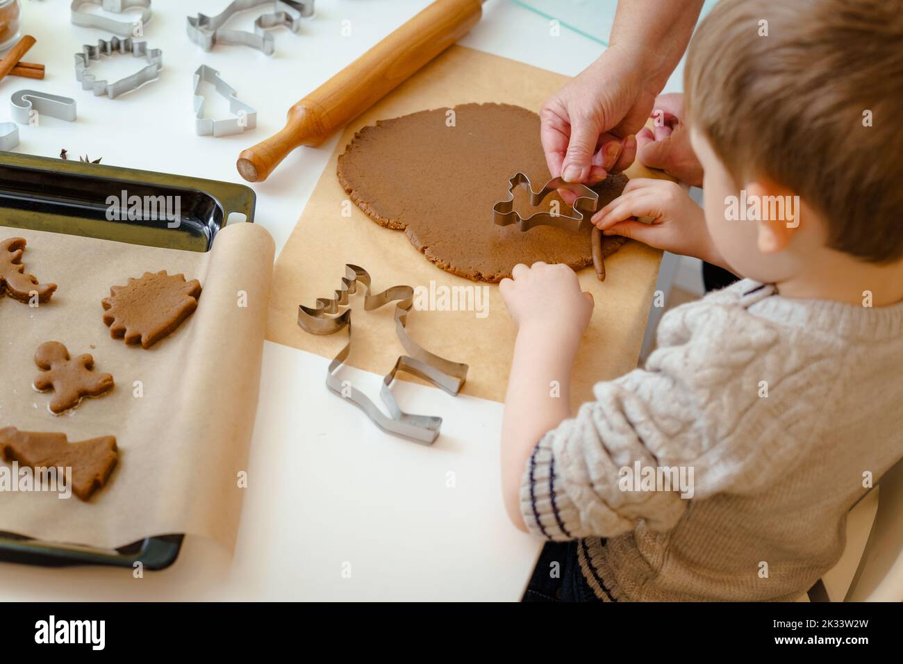 Der Junge schneidet aus dem Teig einen weihnachtlichen Lebkuchenmann in Form eines Hirsches Stockfoto