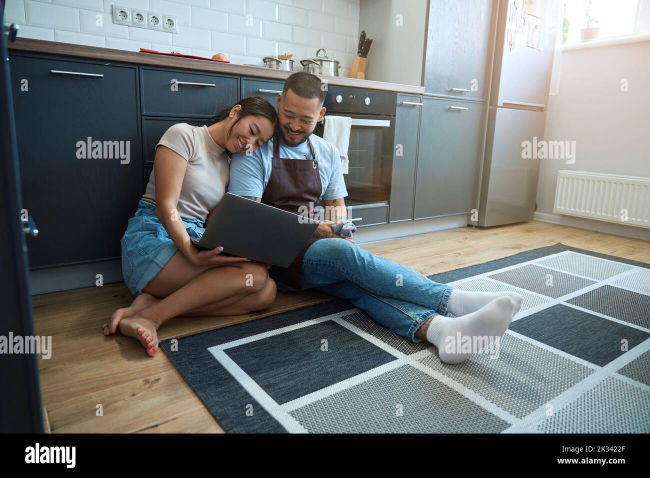 Frau und Mann sitzen mit einem Laptop auf dem Boden Stockfoto