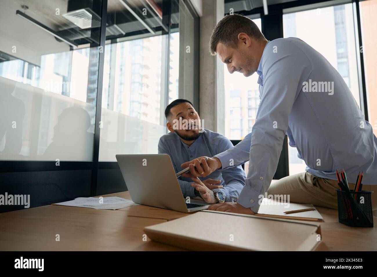 Büromitarbeiter senden Daten von einem Mobilgerät an einen tragbaren Computer Stockfoto