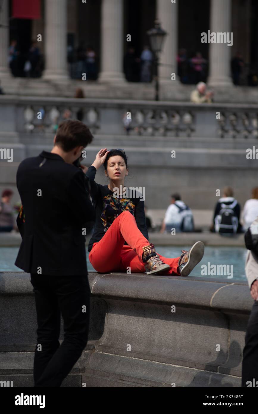 Der Mann fotografiert ein Modell, das auf den Springbrunnen am trafalgar Square in London posiert, Juni 26. 2013, Stockfoto