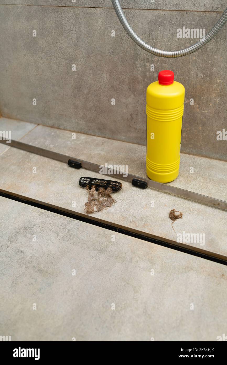 Flüssiger Reiniger in einer gelben Flasche zur Reinigung von Abwasserkanälen. Verwenden von Abflussreinigern zur Reinigung des Duschabflusses. Stockfoto