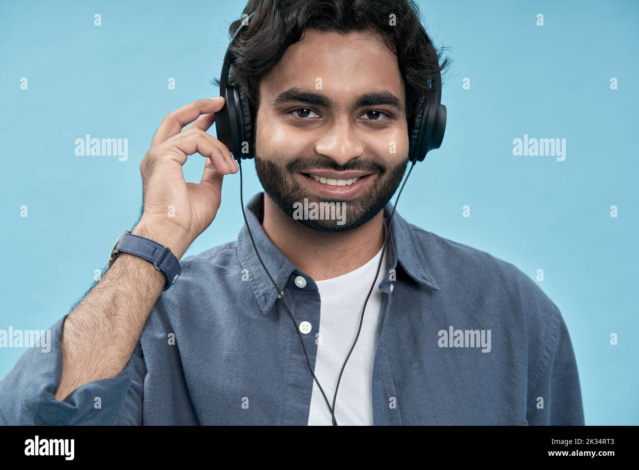 Lächelnder arabischer Mann mit Kopfhörern, der Musik oder Podcast hört. Nahaufnahme Stockfoto