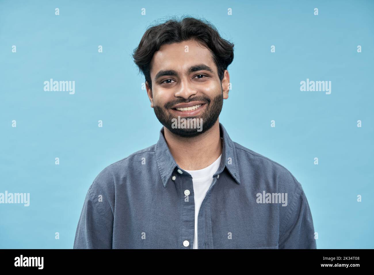 Lächelnder, selbstbewusster junger arabischer Mann, der isoliert auf blauem Hintergrund steht. Stockfoto