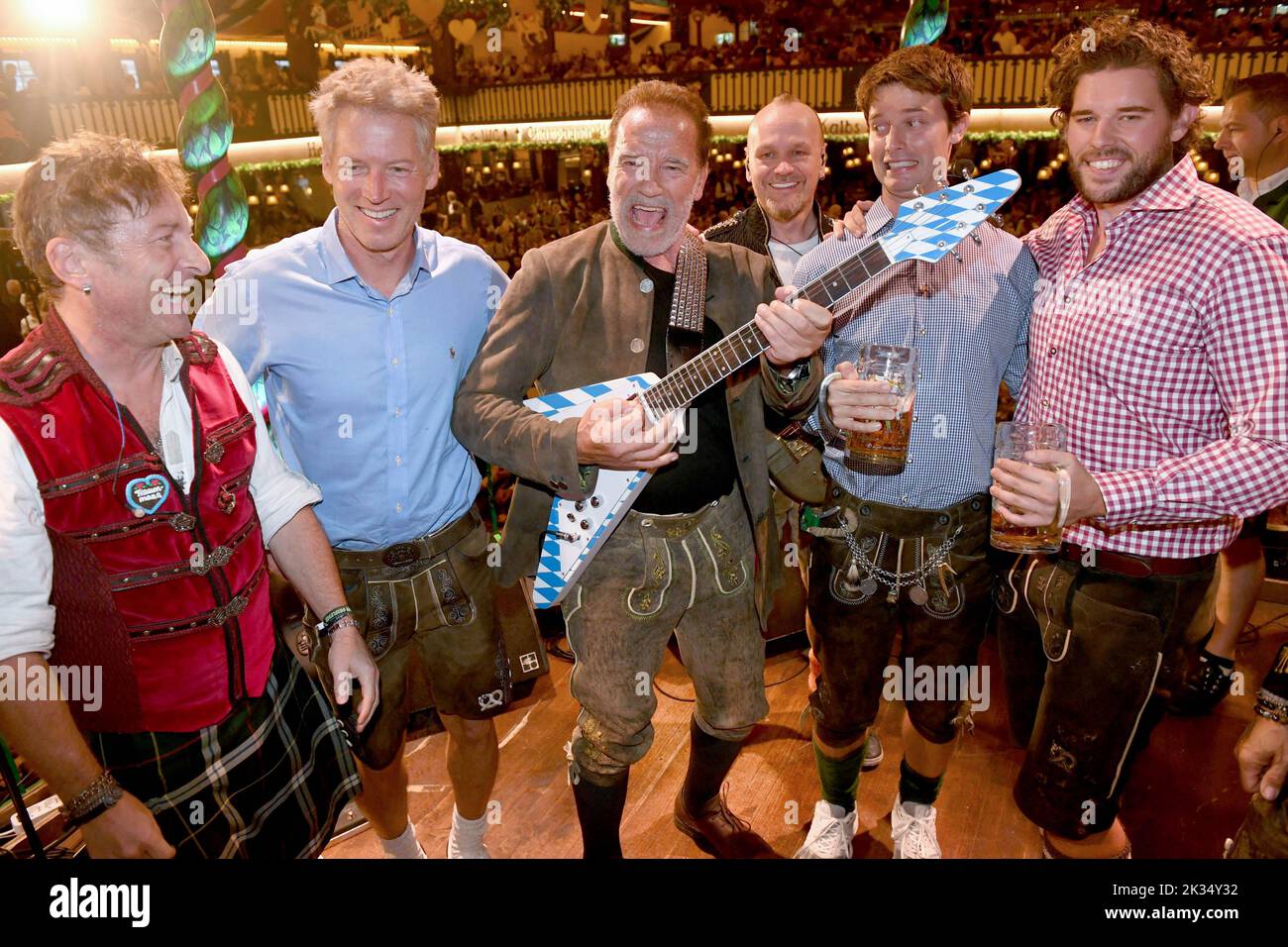 München, Deutschland. 24. September 2022. Schauspieler Arnold Schwarzenegger (3. v.l.) zeigt mit einer E-Gitarre, sein Neffe Patrick knapp Schwarzenegger (2. v.l.) und seine Söhne Patrick Schwarzenegger (2. v.l.) und Christopher Schwarzenegger (r.) auf der Bühne im Festzelt Marstall auf dem Münchner Oktoberfest. Die Wiesn findet vom 17. September bis 3. Oktober 2022 statt. Quelle: Felix Hörhager/dpa/Alamy Live News Stockfoto