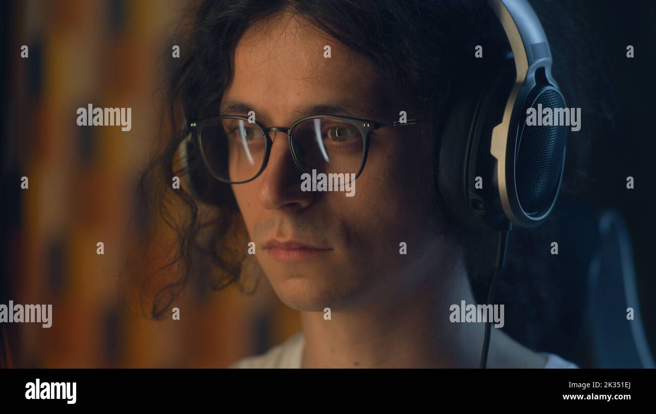 Mann mit Kopfhörern und Brille zu Hause, der an freiberuflichen Projekten arbeitet oder in freier Zeit im Internet surft und Musik hört Stockfoto