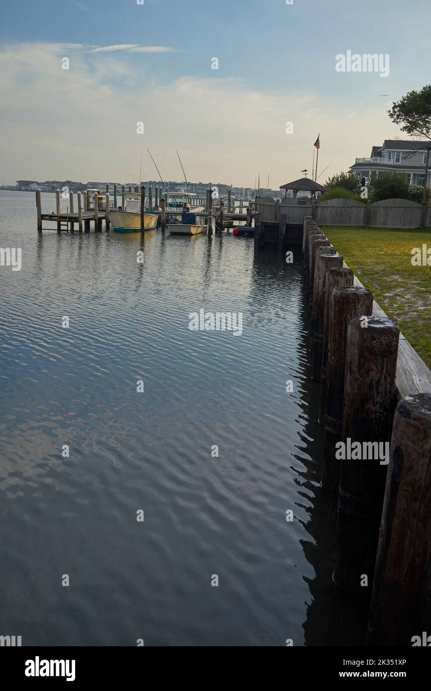 Blick auf die Bucht auf Long Beach Island an der Küste von Jersey. Klarer sonniger Morgen, private Docks mit kleinen Motorbooten, Holzpfählen im Vordergrund Stockfoto
