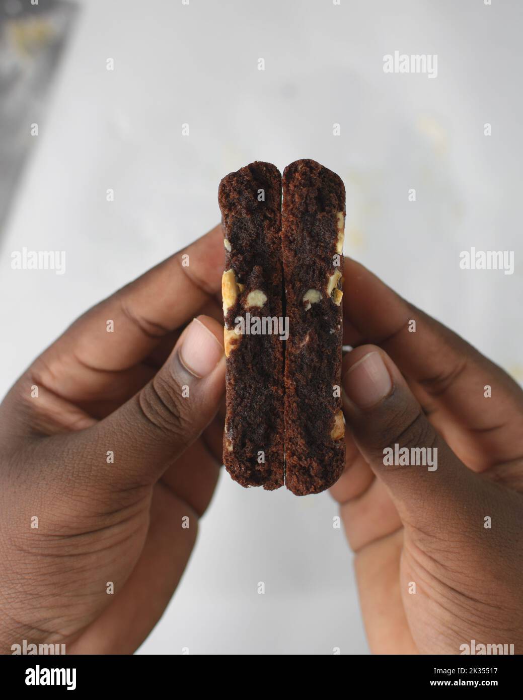 Draufsicht auf Hand mit dreifachem Schokoladenkeksen, flacher Laie von dunklem Schokoladenkekie, Schokoladenkekie in weiblichen Händen Stockfoto