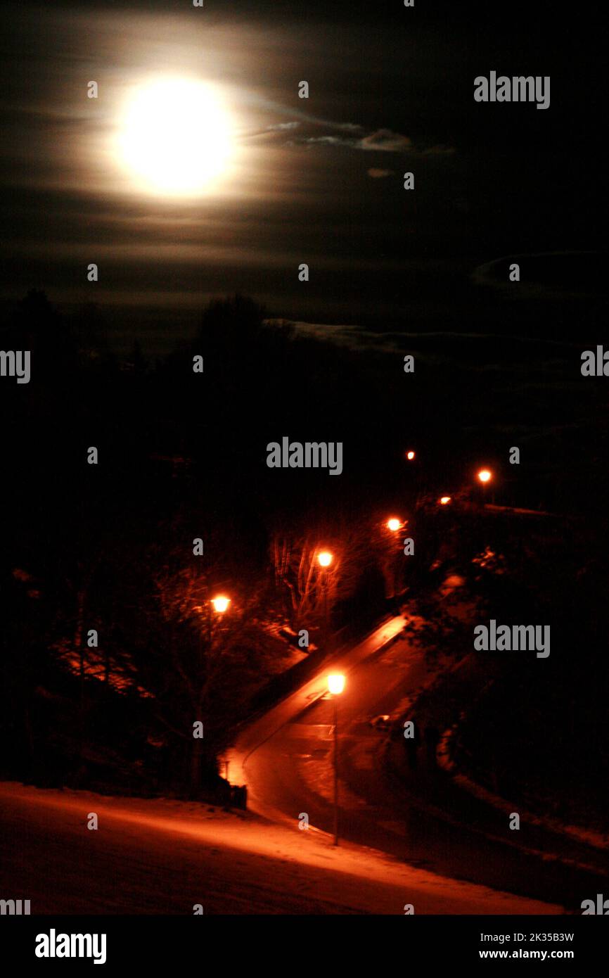 Ein vertikaler Mondschuss über einer Straße bei Nacht Stockfoto