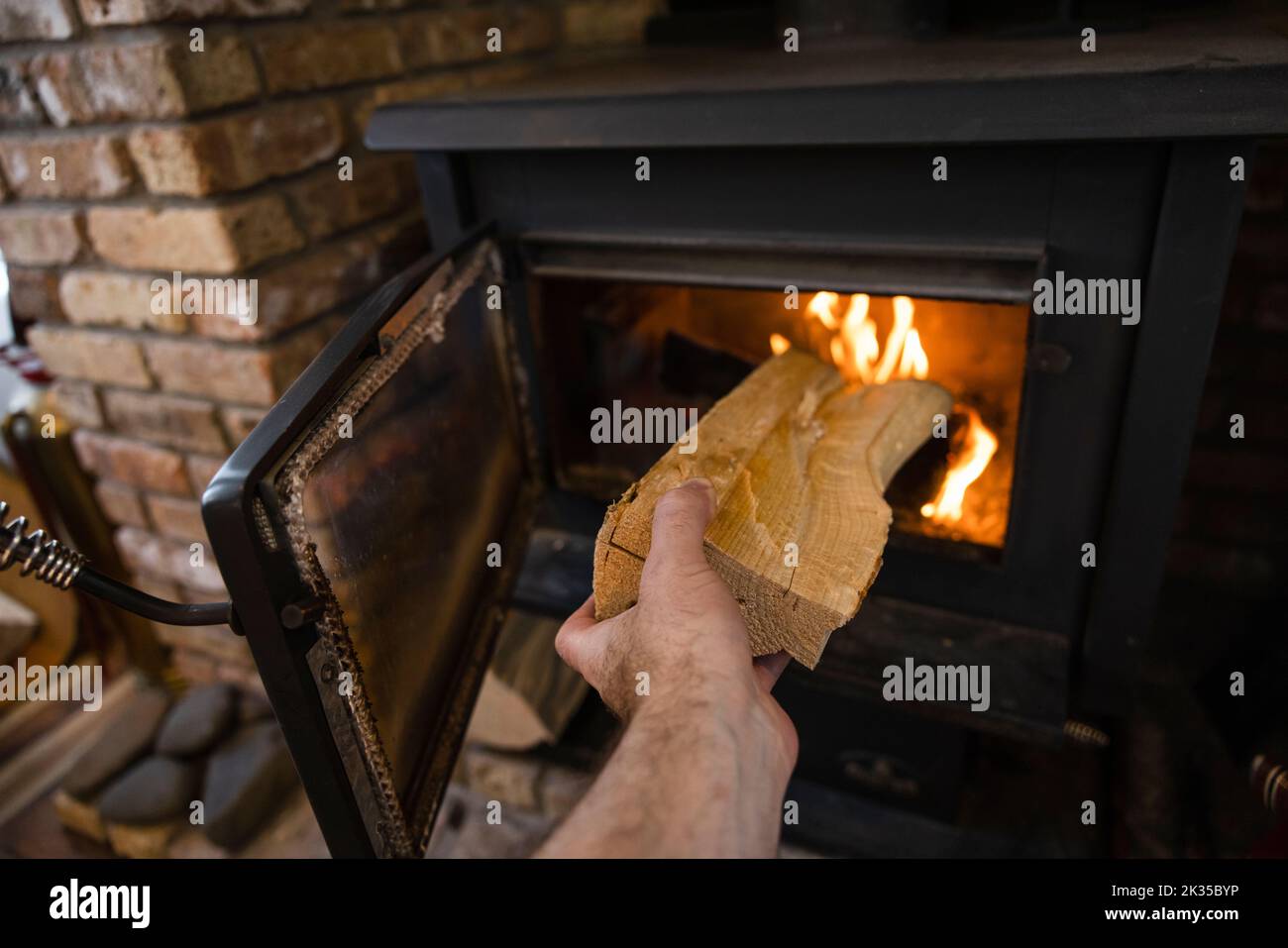POV Hand, die Brennholz in Holzofen Kamin Stockfoto