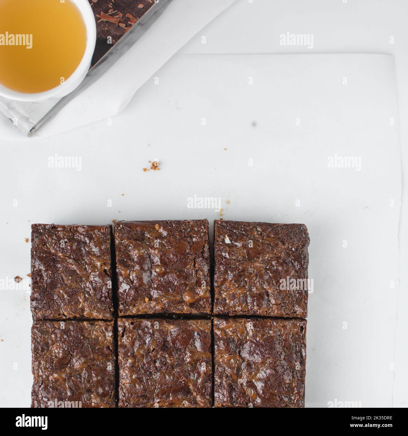 Flache Brownies, in Quadrate geschnittene Brownies, Karamell-Brownies auf weißem Pergamentpapier Stockfoto