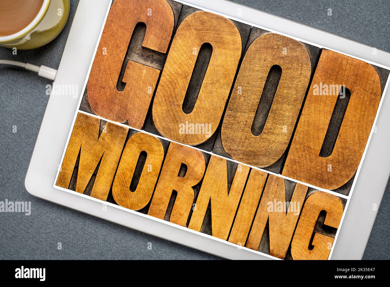 Guten Morgen word Abstract-text in Vintage buchdruck Holz Art Klischees auf einem digitalen Tablette mit einer Tasse Kaffee Stockfoto