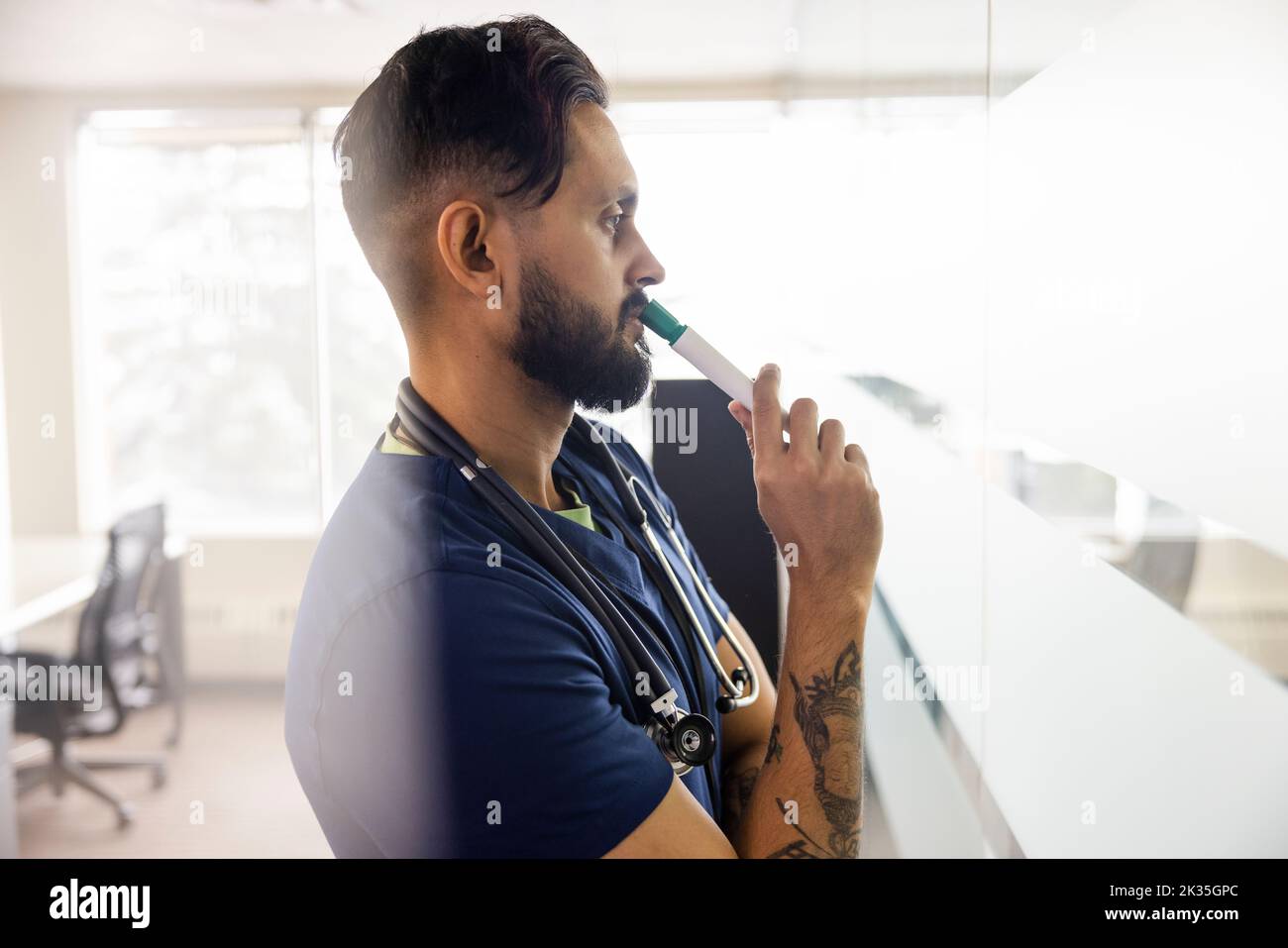 Nachdenklicher männlicher Arzt mit trocken abwischbaren Marker in der Klinik Stockfoto
