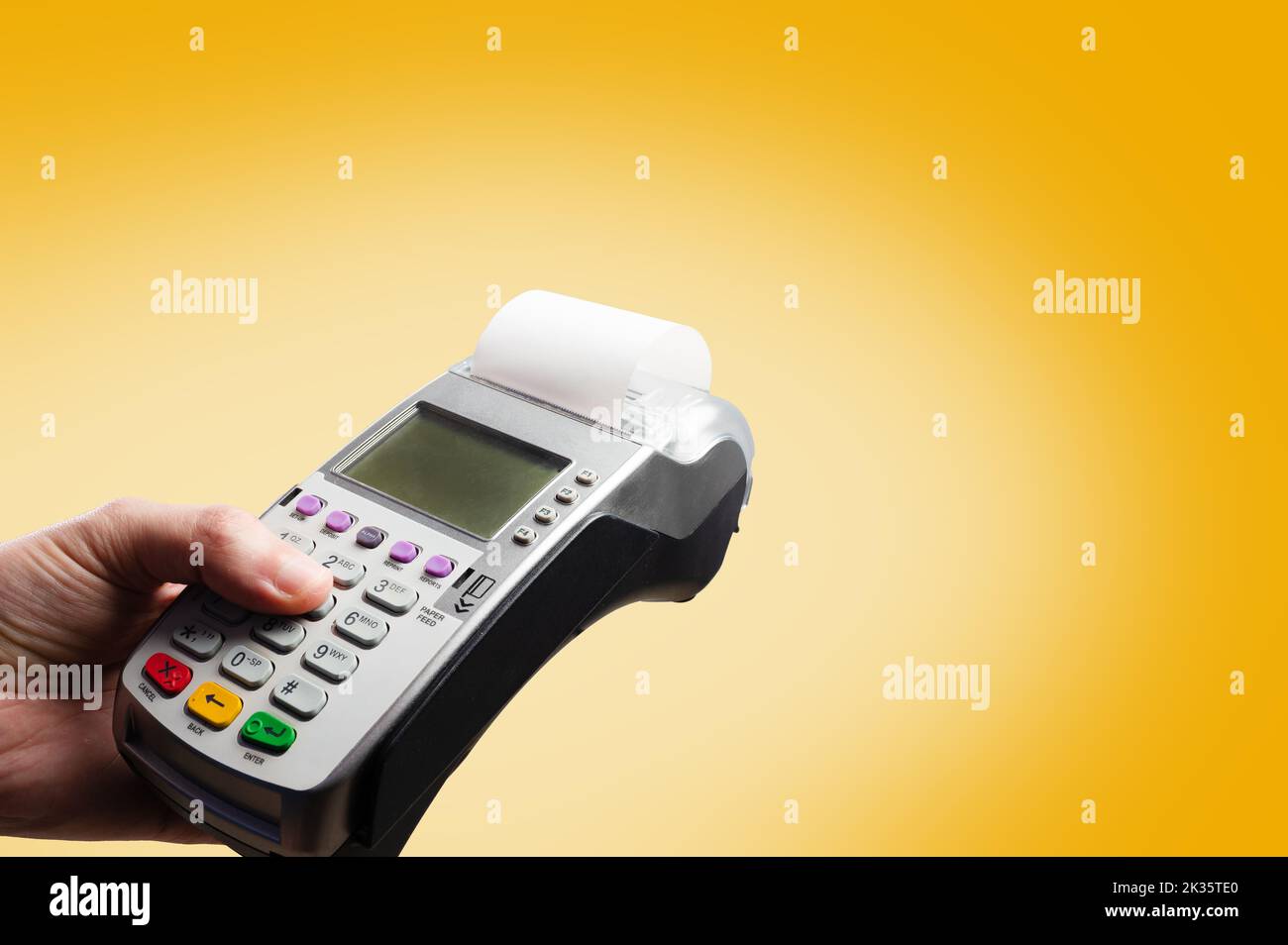 Nahaufnahme. Geldautomaten in der Hand eines Mannes auf gelbem Hintergrund. Minimalismus. Groß- und Einzelhandel, Bank- und Kreditkarten, kontaktloses Bezahlen. Ad Stockfoto