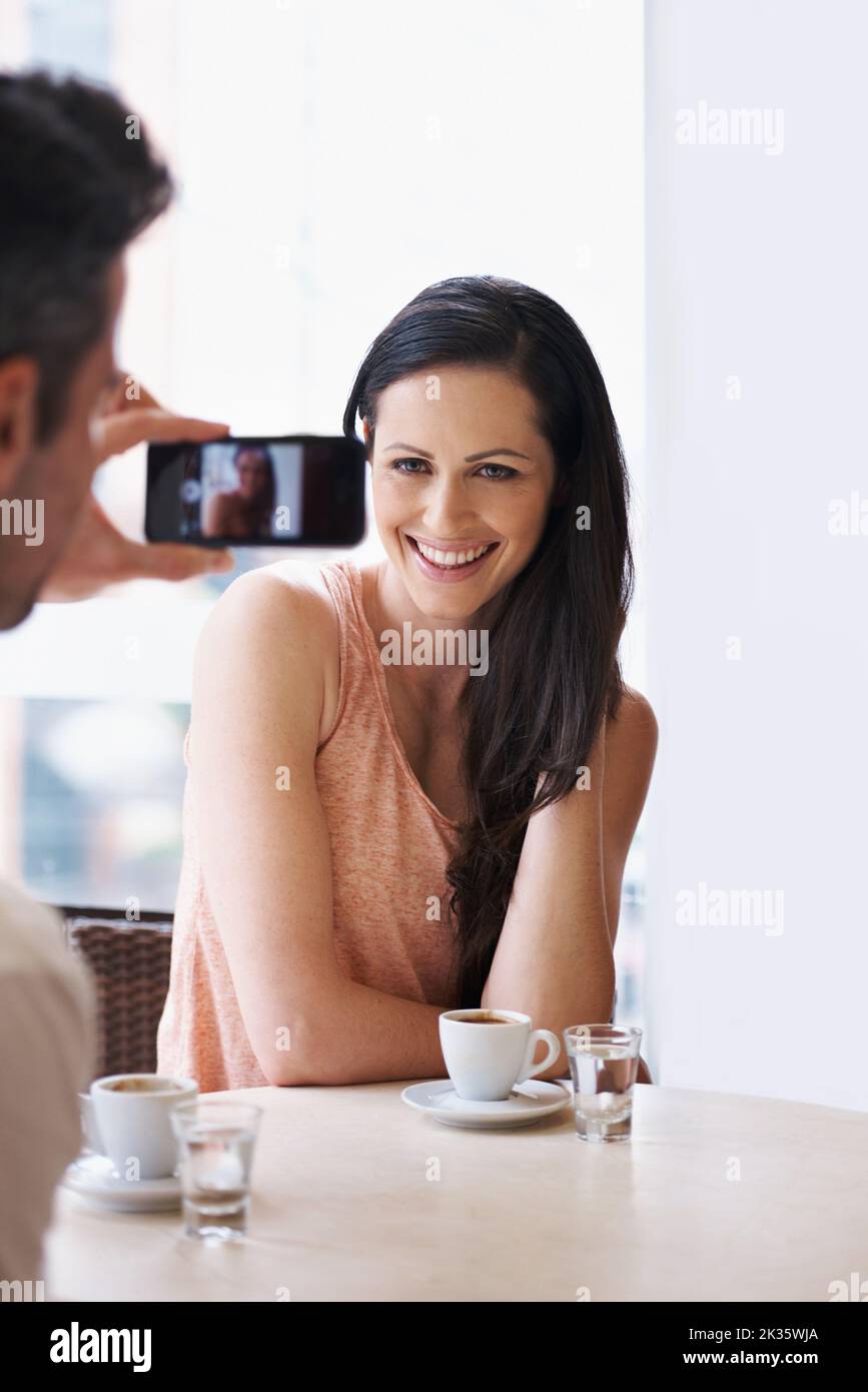 Heute sehen Sie wunderschön aus. Ein Mann, der in einem Café mit seinem Telefon eine Momentaufnahme seiner Frau gemacht hat. Stockfoto