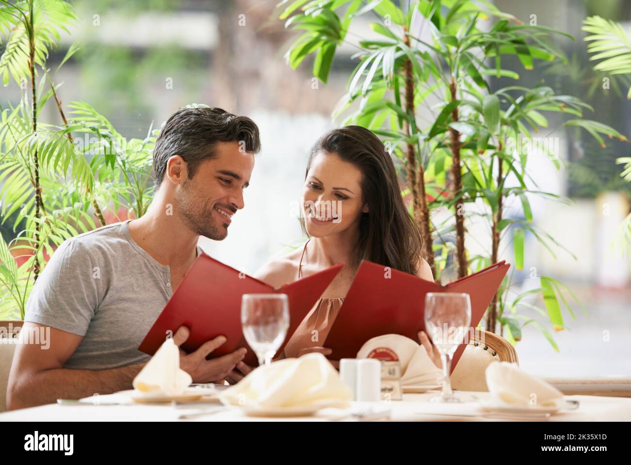Das feine Dining-Erlebnis. Ein glückliches junges Paar, das sich die Speisekarten in einem schicken Restaurant ansieht. Stockfoto