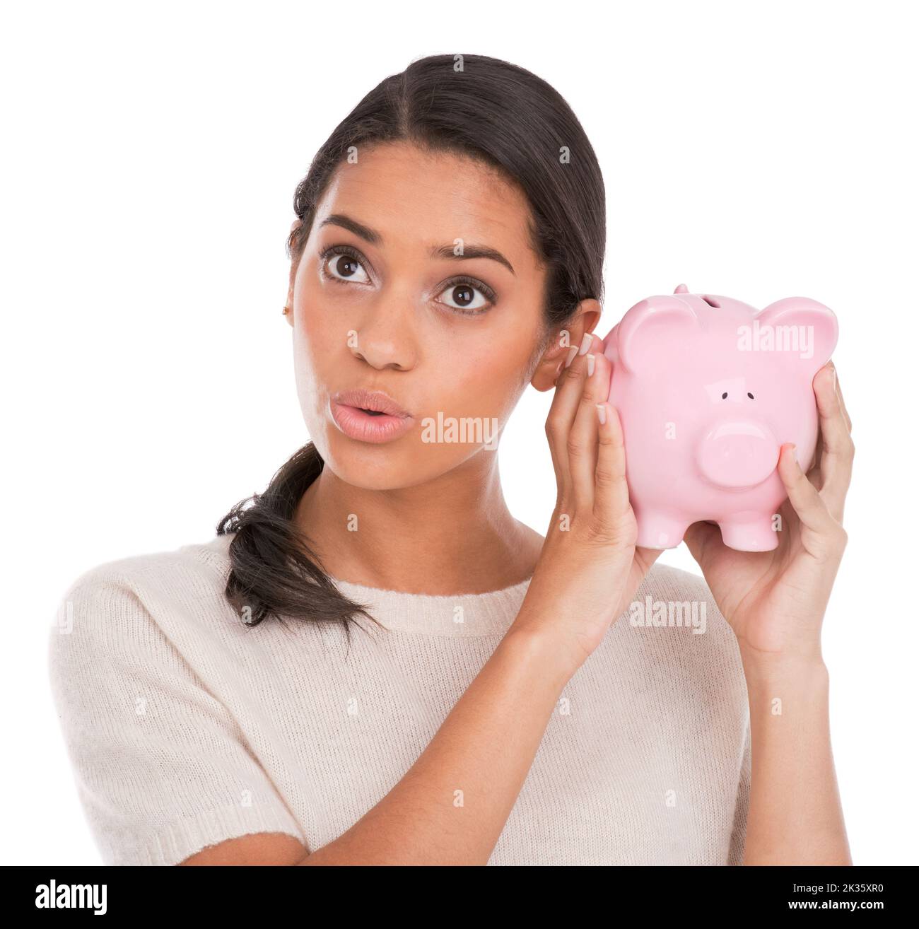 Klingt vielversprechend... eine attraktive junge Frau, die ein Sparschwein hält und hoffnungsvoll aussieht. Stockfoto