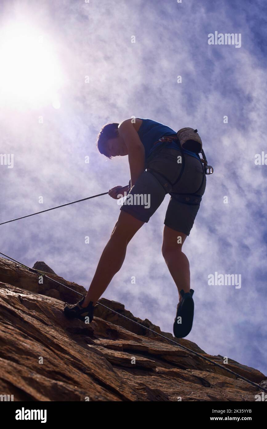 Die einfachen Freuden des Felskletterns. Eine junge Klettererin, die sich auf einen Berg abseilt. Stockfoto