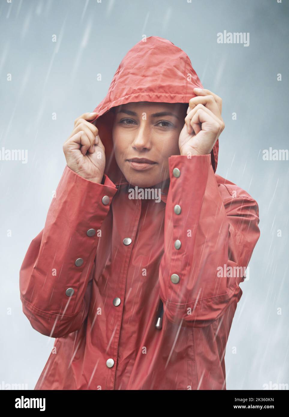 Ich bin nass, wenn es nicht für meine Anorak war. Beschnittenes Porträt einer jungen Frau, die ihre Kapuze hochzieht, während sie im Regen steht. Stockfoto