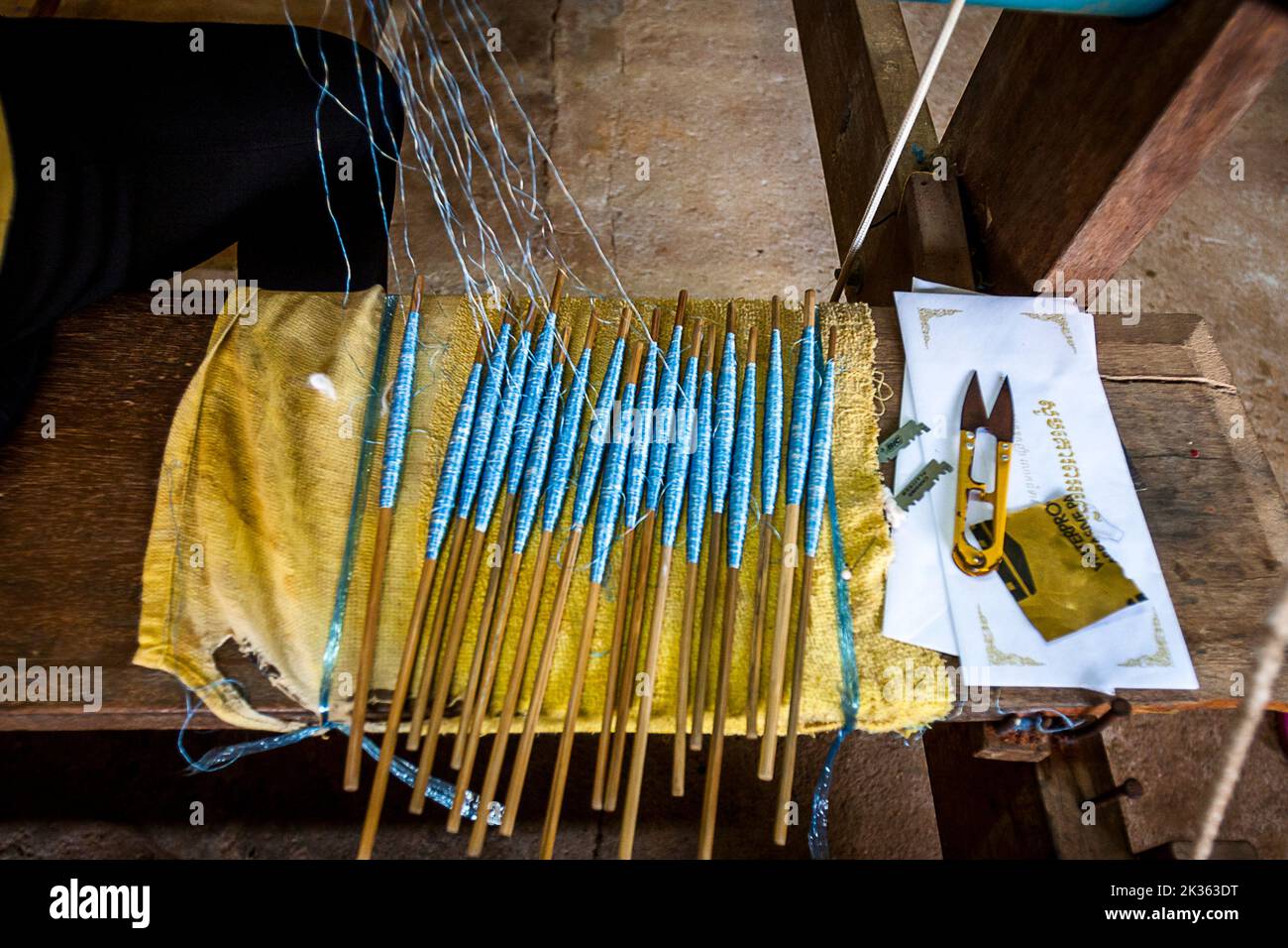 Ein langer Stab blau gefärbter Seide zum Weben von Seidenbekleidung auf einem Tisch. Stockfoto