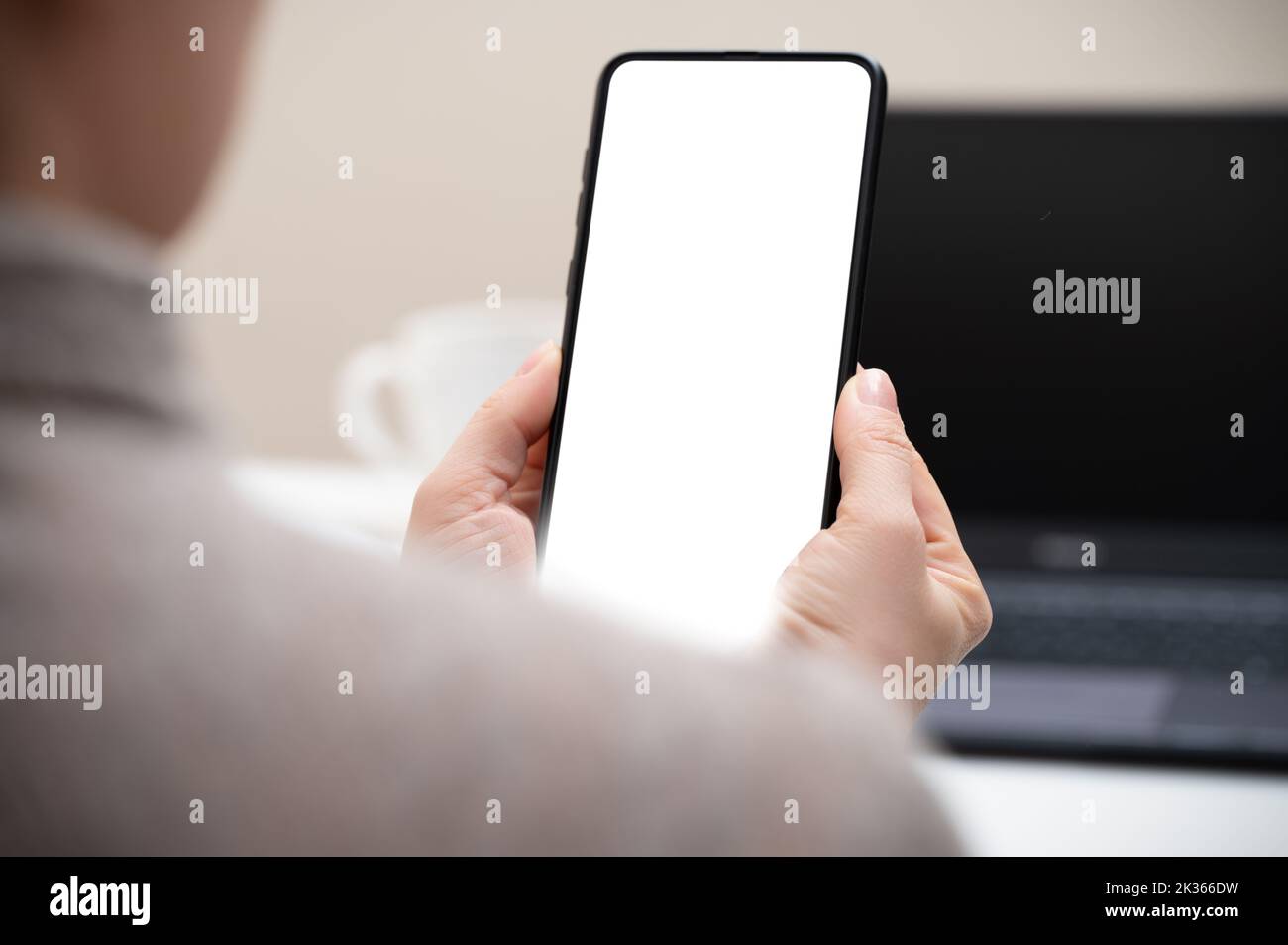 Handy-Modell. Eine kurze Aufnahme einer Geschäftsfrau, die in einem modernen Bürozimmer auf ein Smartphone mit leerem Bildschirm schaut. Frau Hand hält Handy mit leeren s Stockfoto
