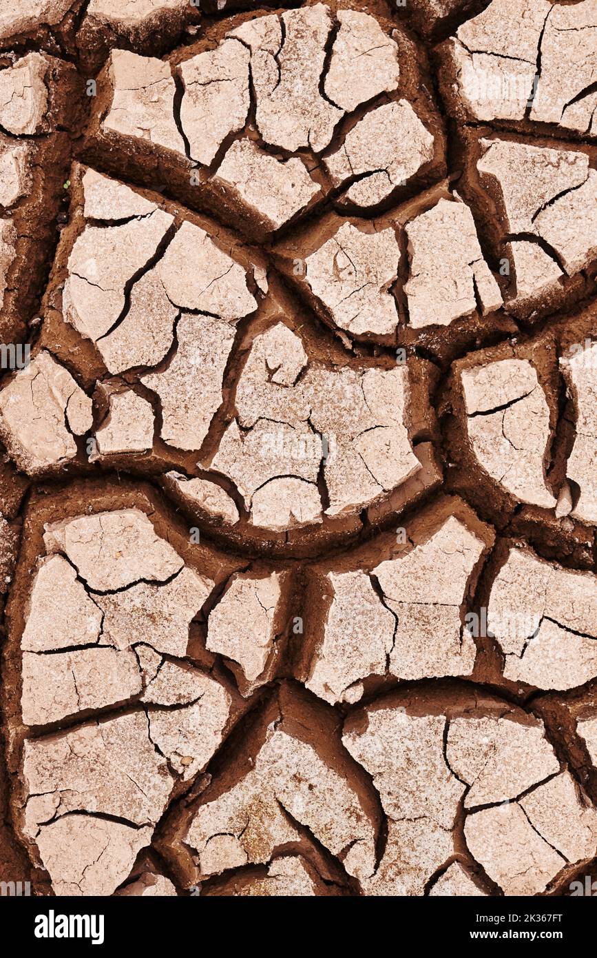 Von der Sommerhitze geknackt. Trockener rissiger Boden in der afrikanischen Landschaft. Stockfoto