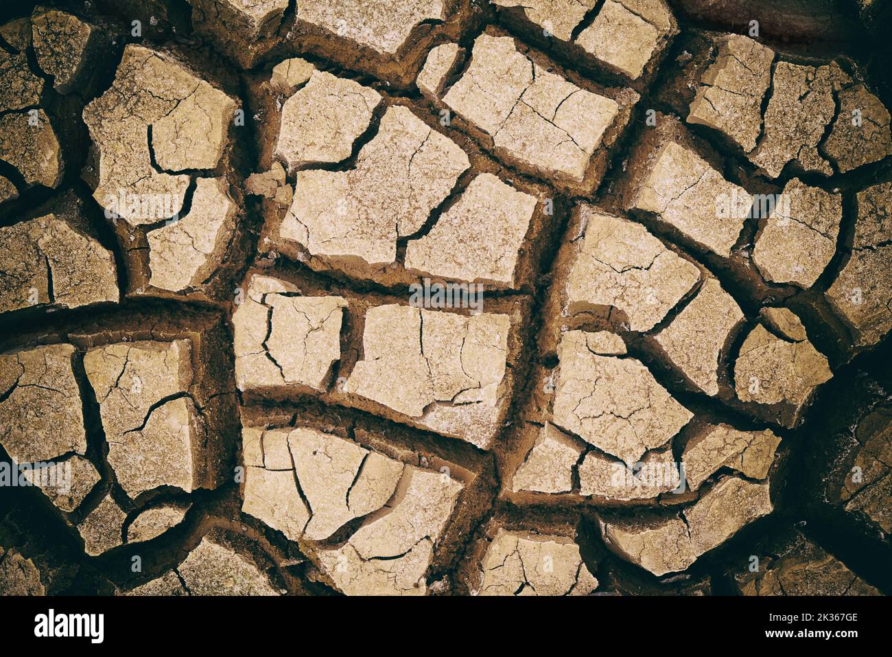 Von der Sommerhitze geknackt. Trockener rissiger Boden in der afrikanischen Landschaft. Stockfoto