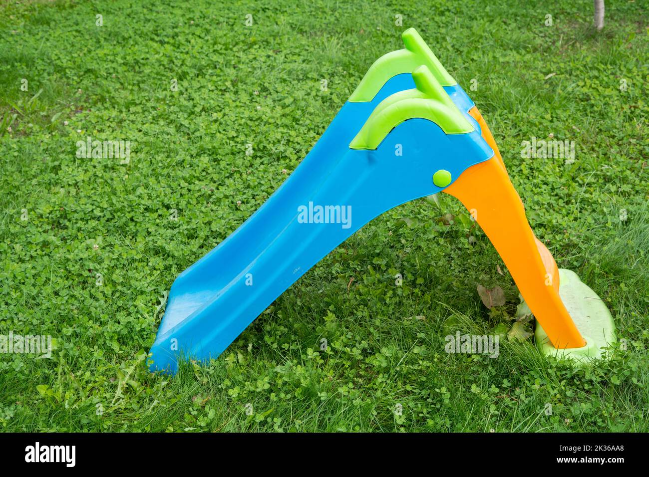 Eine Plastikrutsche im Gras im Park auf dem Kinderspielplatz für kleine Kinder Stockfoto