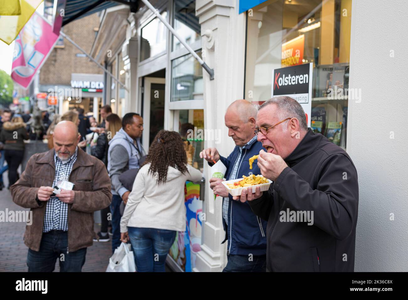 Menschen essen Pommes Frites und frittierte Snacks an der Einkaufsstraße in den Niederlanden Stockfoto