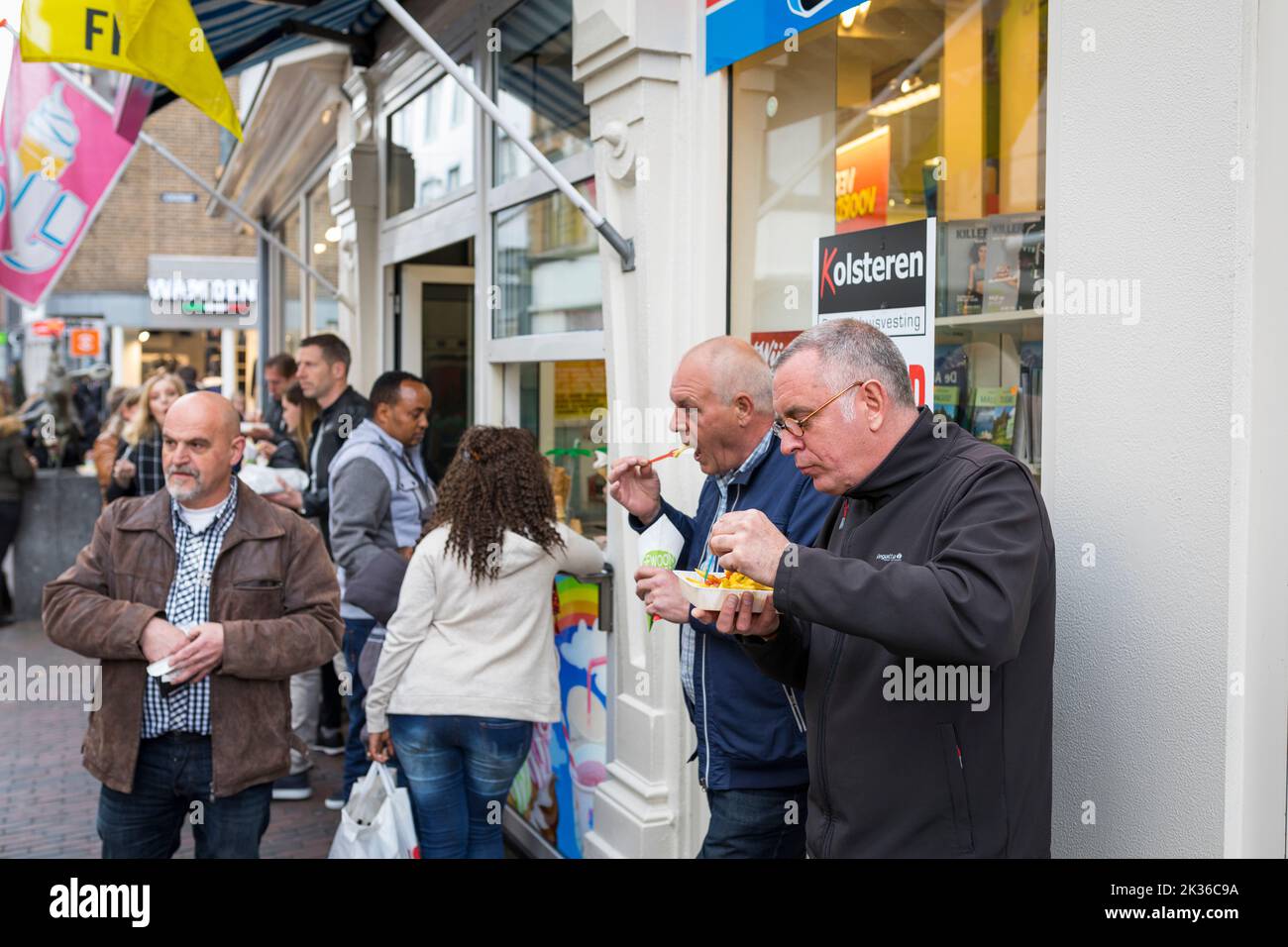 Menschen essen Pommes Frites und frittierte Snacks an der Einkaufsstraße in den Niederlanden Stockfoto