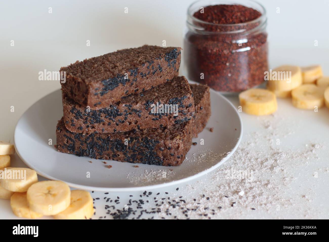 Ragi-Kochbananen-Kuchen. Glutenfreier Teekuchen aus Finger-Hirse-Mehl und pürierten reifen Kochbananen, darauf mit schwarzen Sesamkörnern bestreut. Auf Weiß geschossen Stockfoto