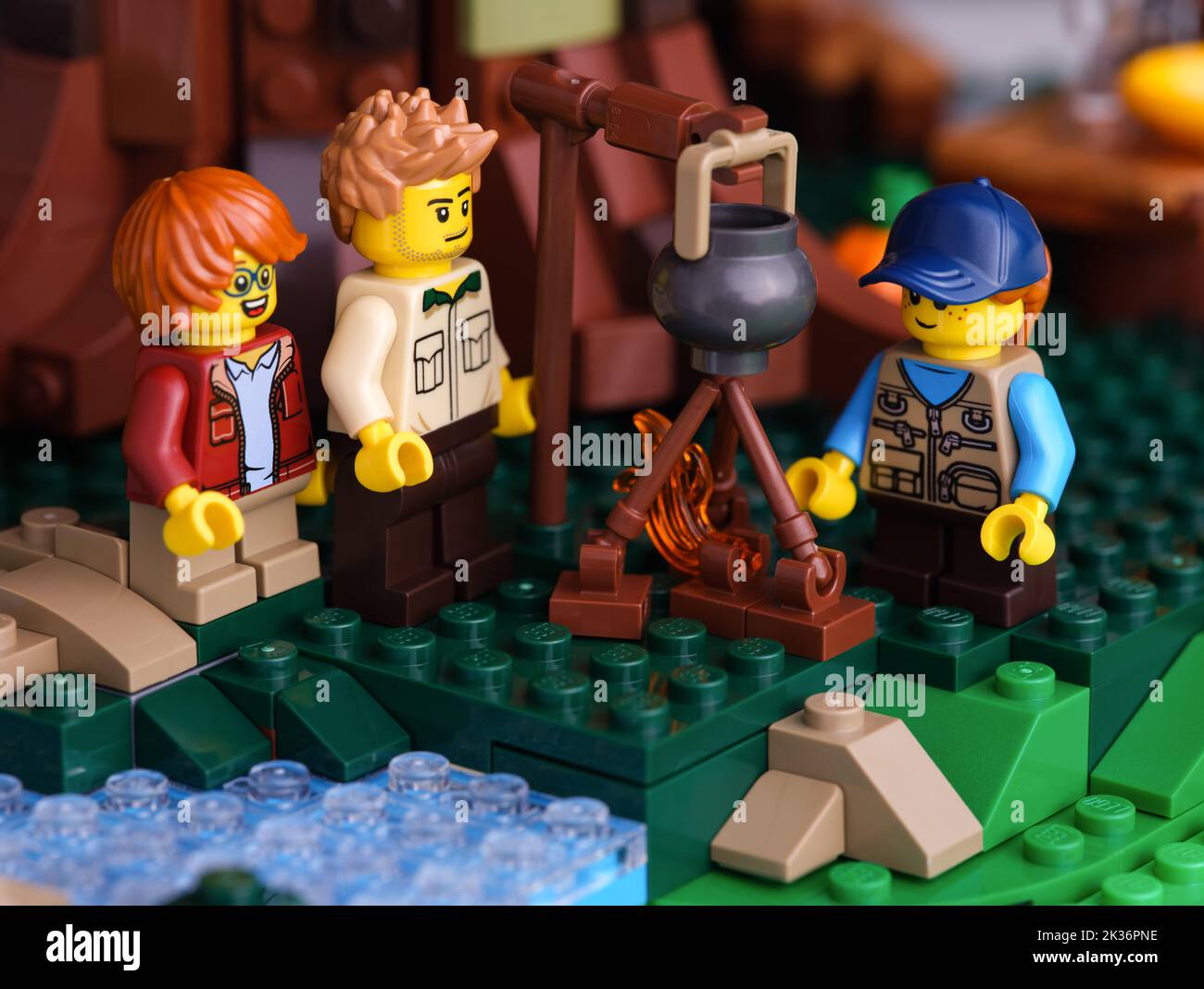 Tambow, Russische Föderation - 22. Juni 2022 drei Lego Minifiguren - Mann und zwei Kinder, die am Lagerfeuer Essen kochen. Nahaufnahme Stockfoto