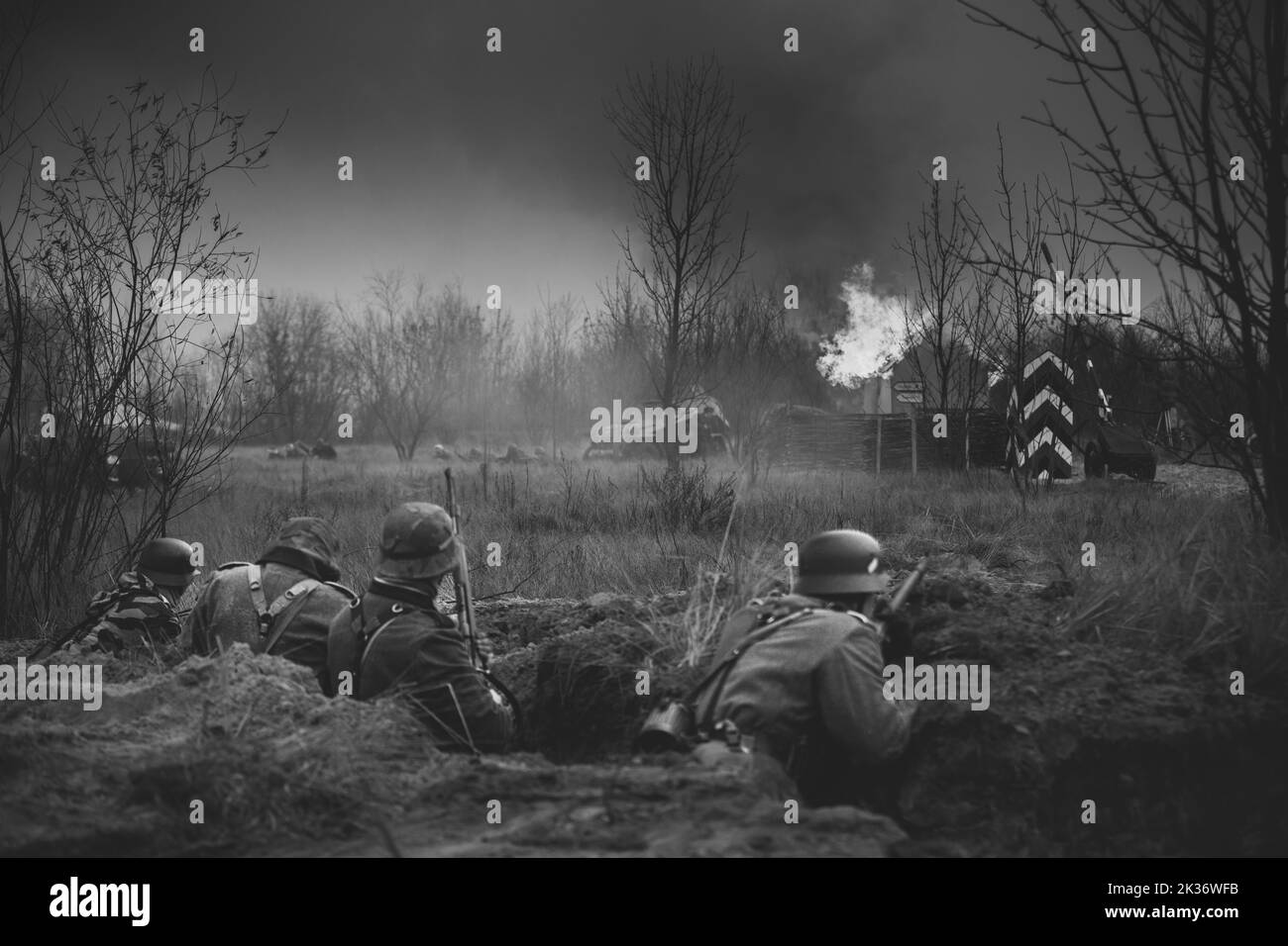Re-enactors gekleidet als Wehrmachts-Infanteriesoldaten des Zweiten Weltkriegs, die defensiv im Graben kämpfen. Defensive Position. Rauchwand. Wird gebaut Stockfoto