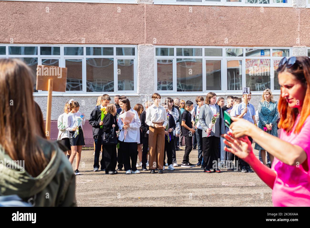 Tomsk Russland September 1,2022 Kinder gehen zurück in die Schule, erster Schultag.glücklich lächelnde Lehrer und Schüler auf dem Schulhof am Tag des Wissens. Oder Stockfoto