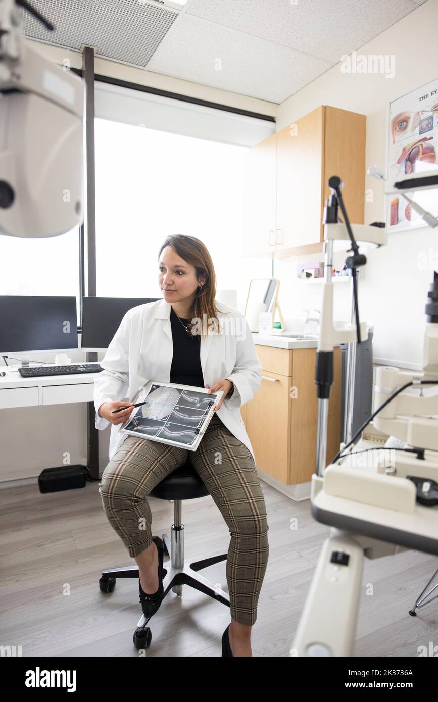Weibliche Optometristin erklärt Retina-Scans im Optometrie-Untersuchungsraum Stockfoto