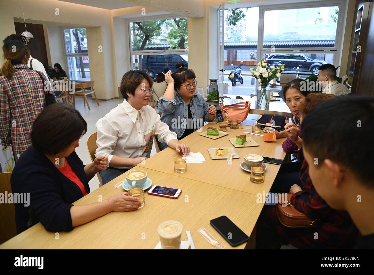 (220925) -- XI'AN, 25. September 2022 (Xinhua) -- Chen Jiayue (2. L), eine hörgeschädigte Barista, kommuniziert mit Familienmitgliedern anderer hörgeschädigter Menschen in ihrem eigenen Café in Xi'an, der Hauptstadt der nordwestlichen Provinz Shaanxi, am 24. September 2022. Der Internationale Tag der Gehörlosen fällt jeden September am vierten Sonntag. Seit 2019 bietet die Shaanxi Urban Economy School kostenlose Barista-Schulungen für Hörgeschädigte an. Die Auszubildenden können während des Trainingsprogramms Kenntnisse über die Kaffeeherstellung und den Betrieb von Cafés erlernen, was ihnen helfen könnte, den Weg für den Start zu ebnen Stockfoto