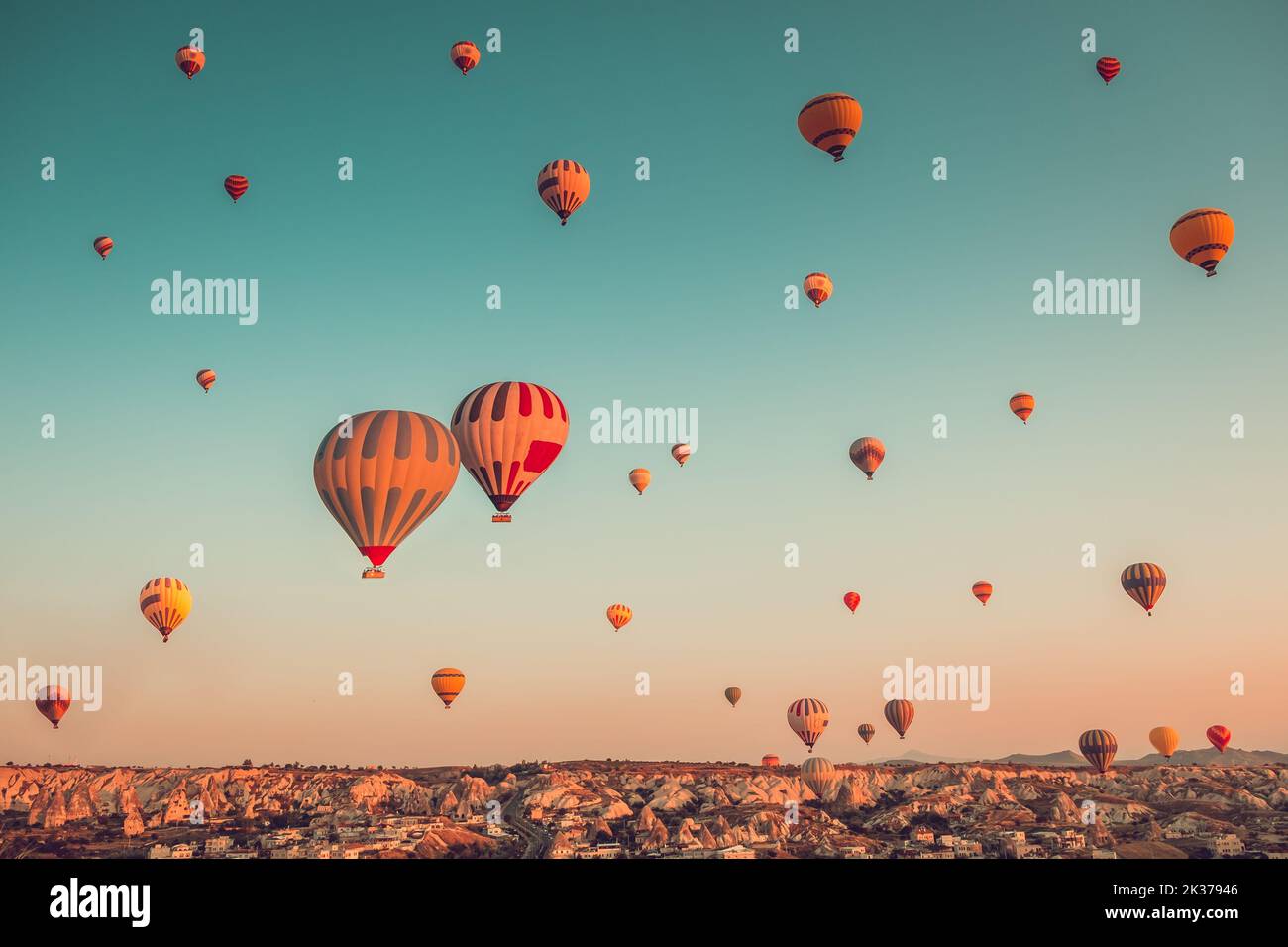 Tausende von bunten Heißluftballons fliegen über die Berge - Cappadocia-Panorama, Sonnenaufgangsansicht. Goreme Tal weite Landschaft. Vintage retro orange blau Toning Filter. Tourismus, Reisen, Urlaub Stockfoto