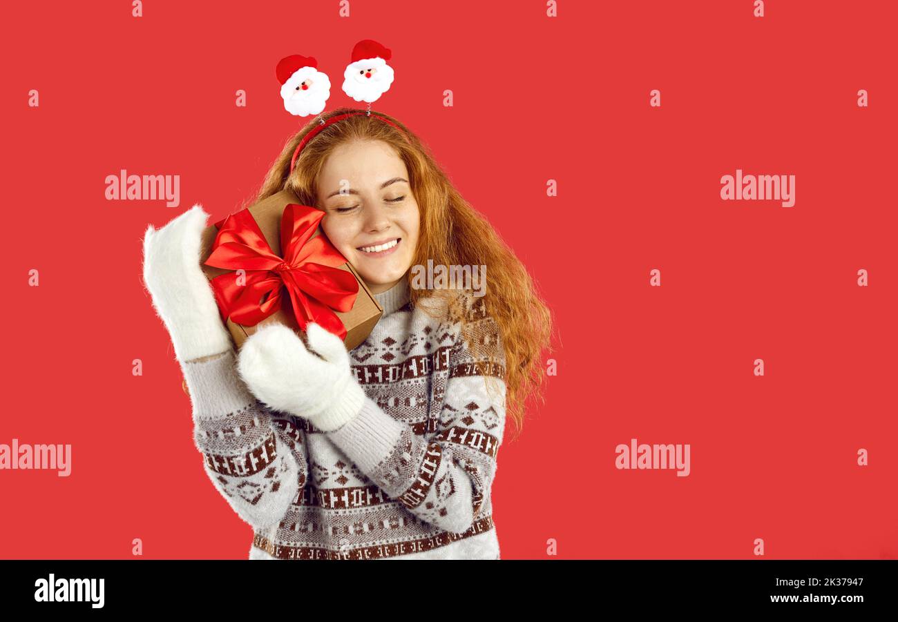 Glückliche junge Frau hält schöne Weihnachtsgeschenk isoliert auf rotem Hintergrund Stockfoto