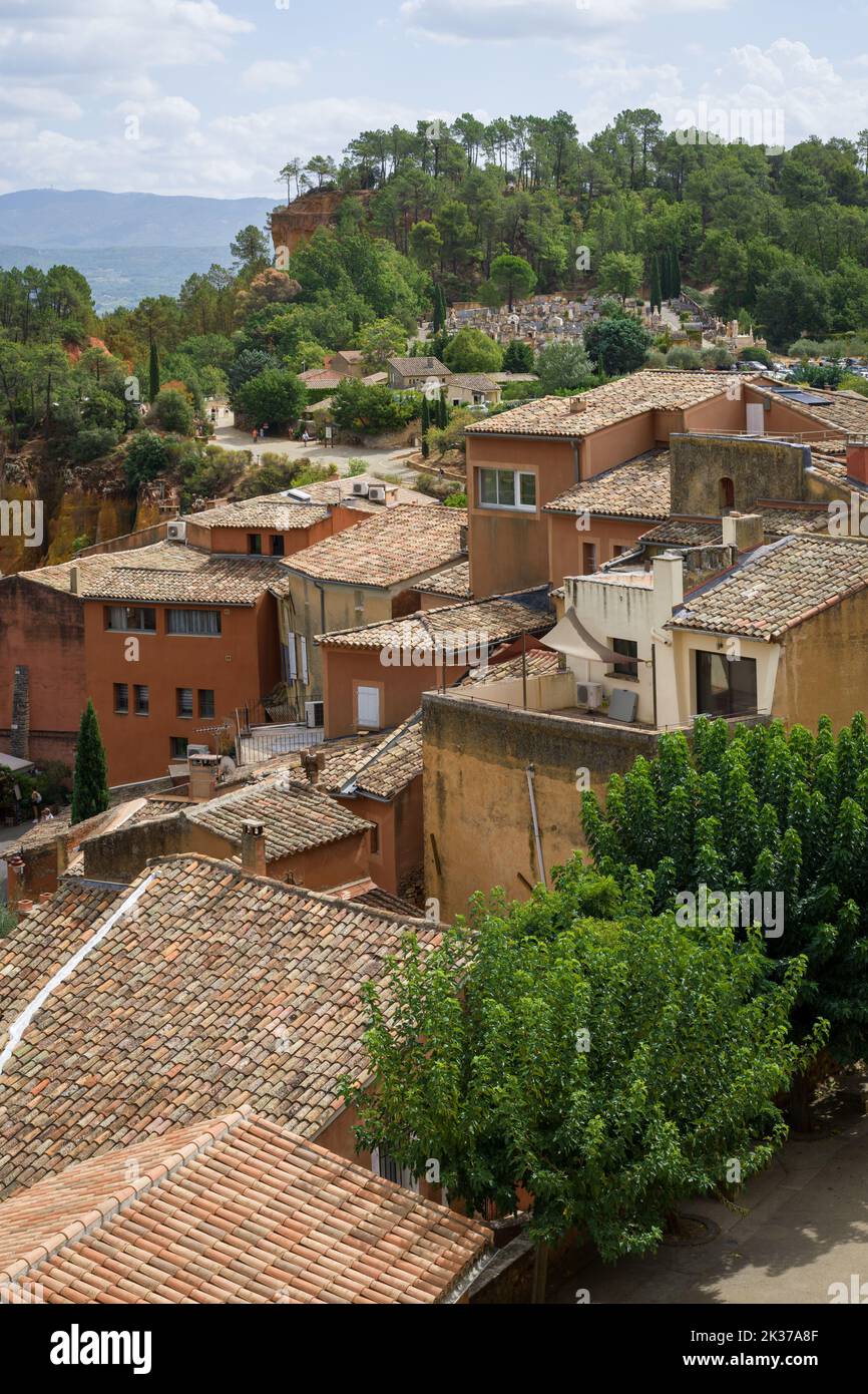 Das hochgelegene Dorf Roussillon (Südfrankreich) mit dem Beginn des Ocher Trails im Hintergrund. Stockfoto