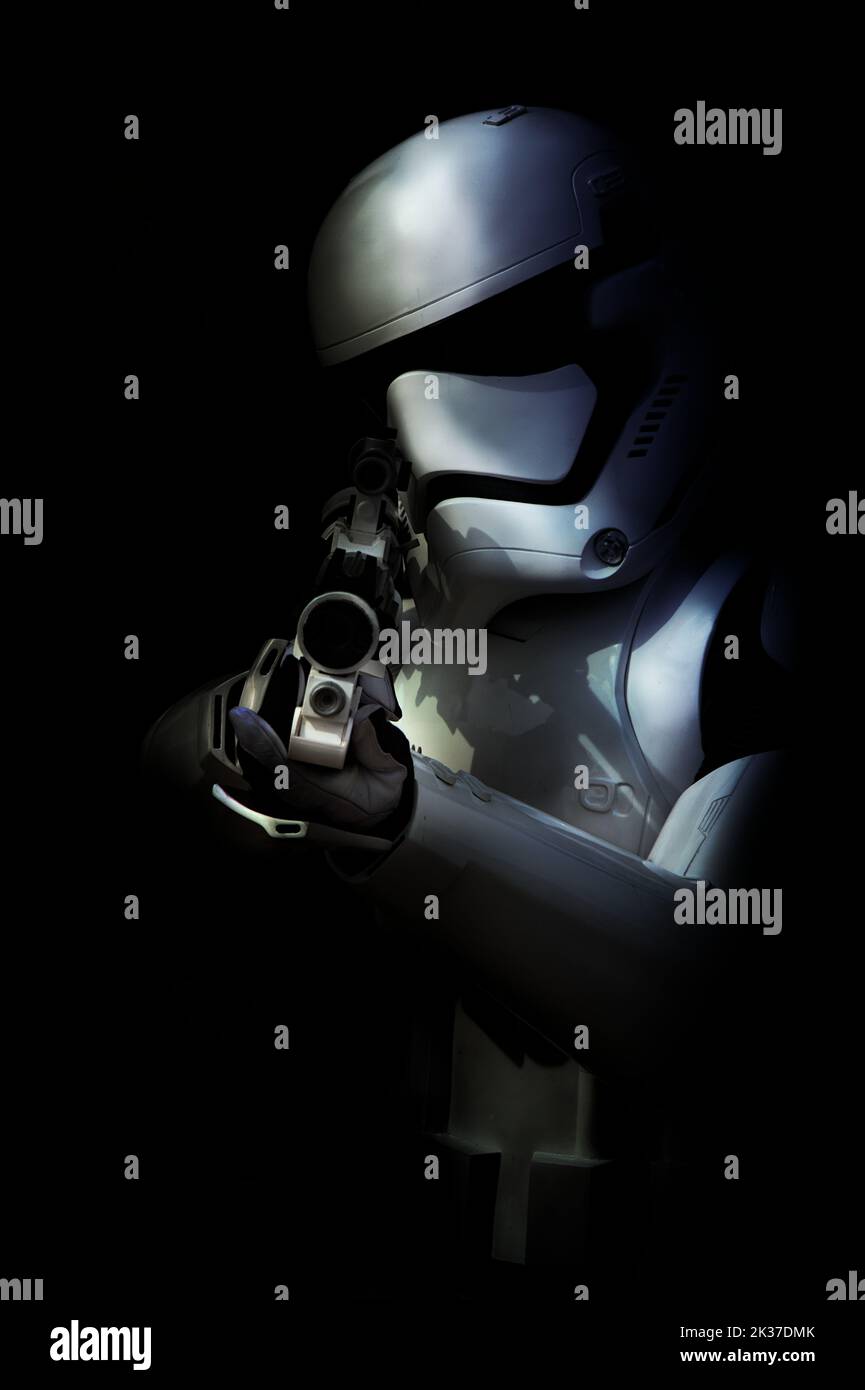 Moody Chiaroscuro Bild einer Person in Einem Star Wars Stormtrooper Kostüm, die auf bedrohliche Weise auf das Christchurch Fest mit seiner BlasTech E-11 Blaster Gun zeigt Stockfoto