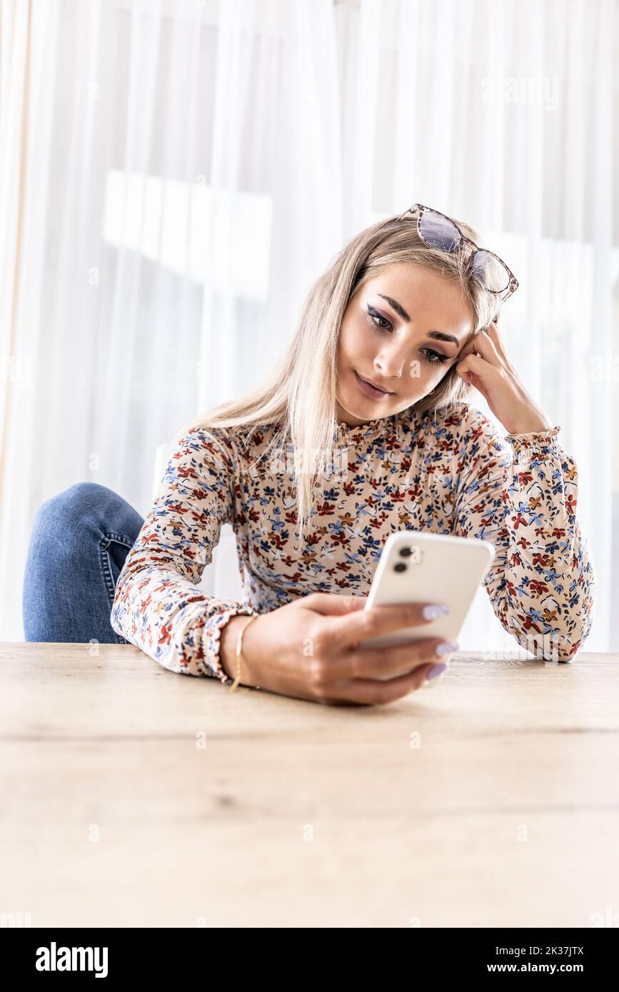 Eine junge Frau nutzt ein Smartphone, schreibt eine SMS oder durchsucht soziale Netzwerke. Stockfoto