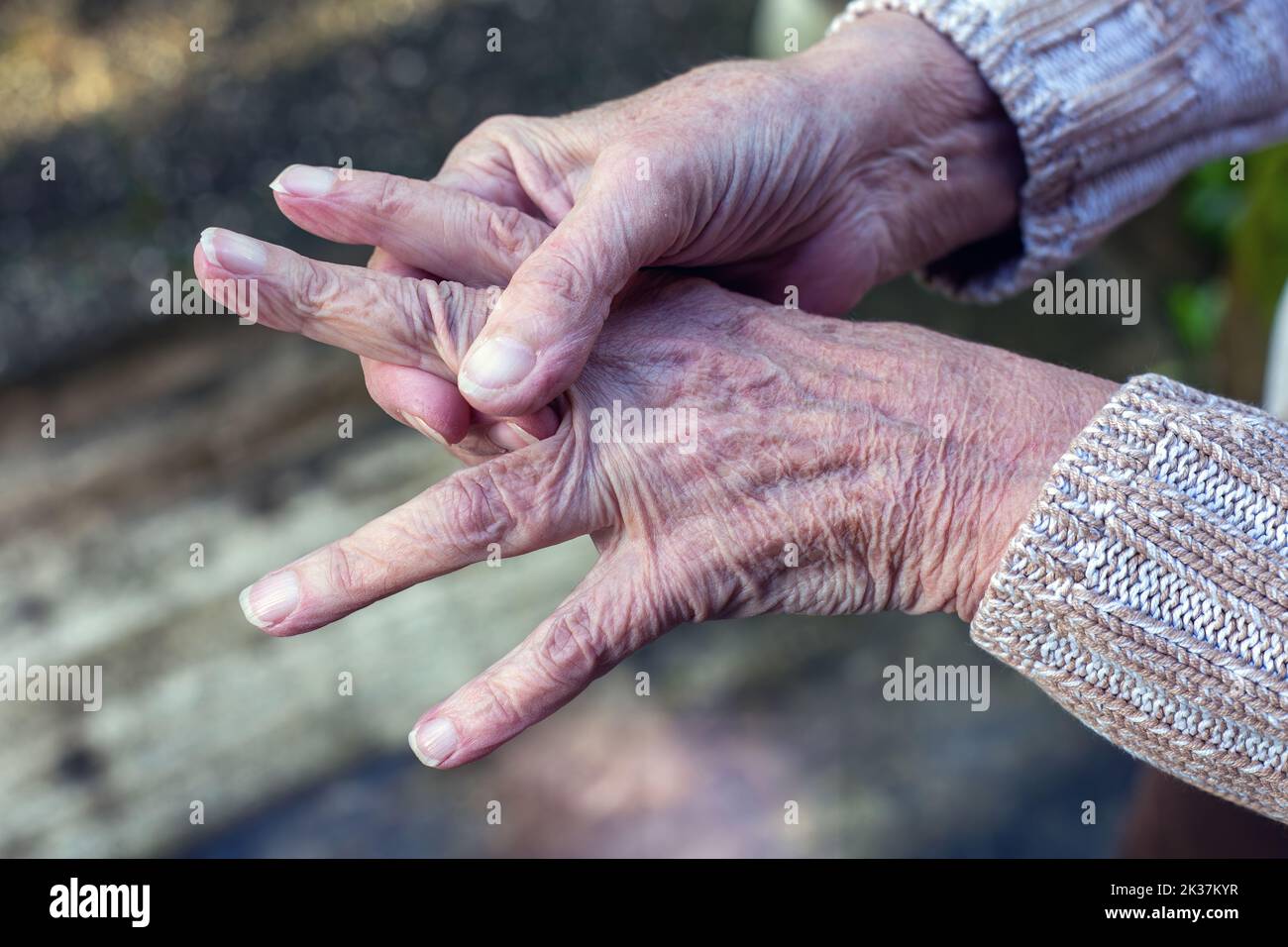 Nahaufnahme einer alten Frau, die sich die Hände reibt Stockfoto