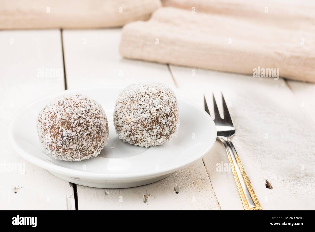 Kokoskuchen, Name Kokoskugel. Gefüllt mit gemischter Füllung. Traditionelles Weihnachtsdessert, ideal für die langfristige Lagerung. Serviert auf einem weißen Retro-Tisch. Stockfoto