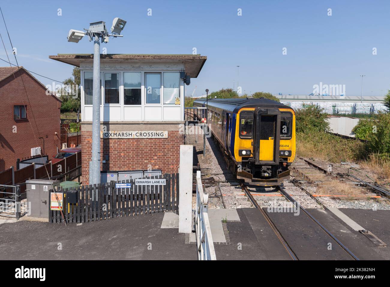 East Midlands Eisenbahnzug der Klasse 156, der die mechanische Eisenbahnsignalbox am Oxmarsh Crossing auf der Barton-Linie, Lincolnshire, Großbritannien, passiert Stockfoto