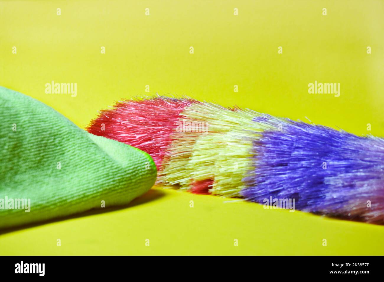 Der farbige Staubwedel und das Tuch fangen den Staub auf den Oberflächen des Haushalts auf. Stockfoto