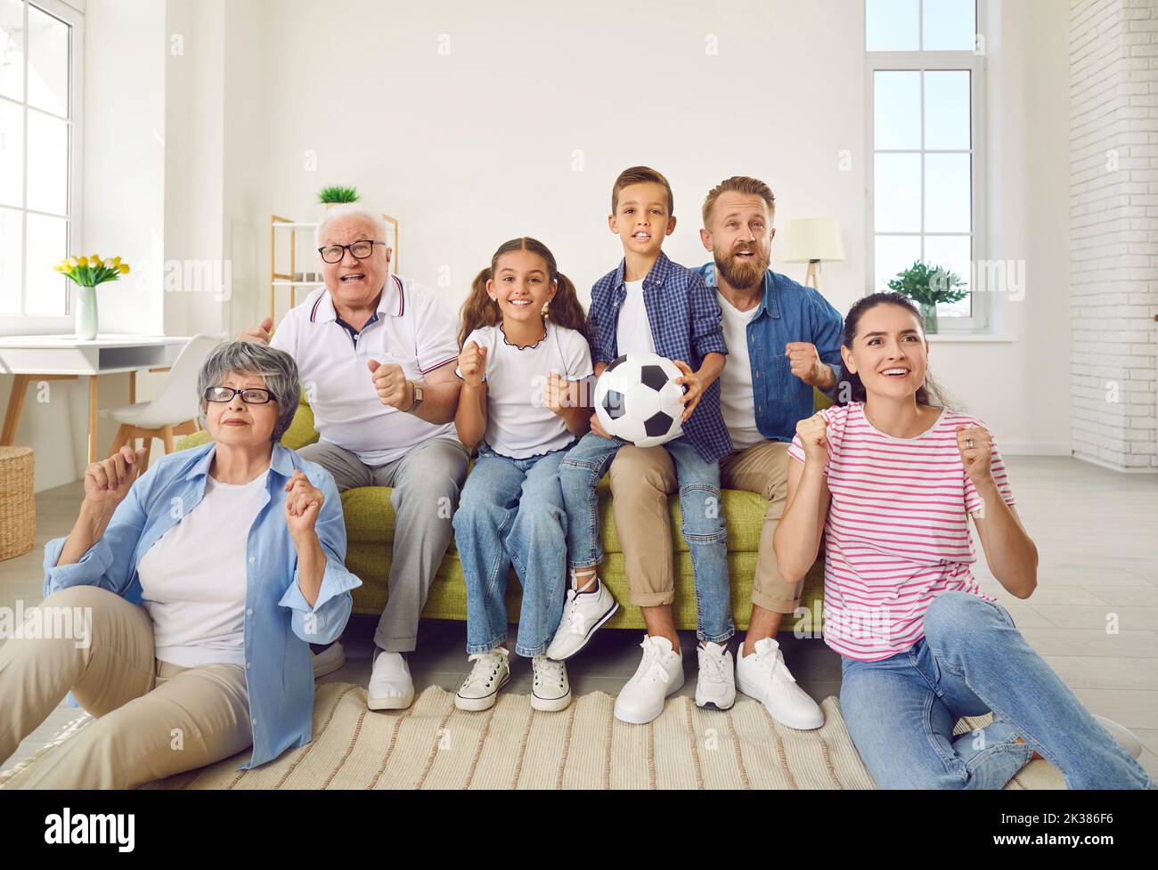 Glückliche, aufgeregte Familie, die zu Hause auf dem Sofa sitzt und Fußball im Fernsehen guckt Stockfoto